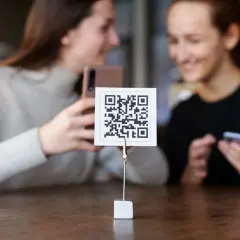 Dwie dziewczyny próbują zeskanować kod QR aparatem telefonu. Proste jak budowa cepa!