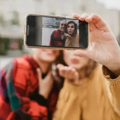 Dwie przyjaciółki robią sobie selfie telefonem. Chcesz wywołać zdjęcia z telefonu? To proste!