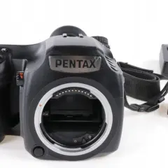 Czarna lustrzanka cyfrowa Pentax z paskiem i akcesoriami, gotowa do aukcji na Allegro.
