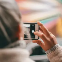 Dłoń trzyma smartfon, robiąc zdjęcie. Aby uzyskać czyste ujęcia, pamiętaj, jak wyczyścić aparat w telefonie.