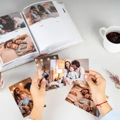 Otwarty album ze zdjęciami rodzin i ręce trzymające odbitki zdjęć.