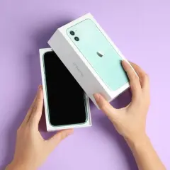Ręce rozpakowują zielony iPhone 11. Aparat tego modelu pozwala robić świetne zdjęcia.