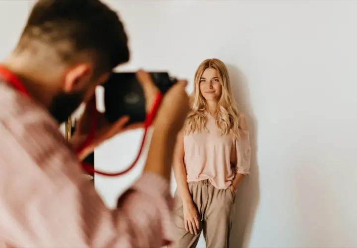 Fotograf robi zdjęcie uśmiechniętej blondynce. Zastanawiasz się, ile kosztuje sesja u fotografa?