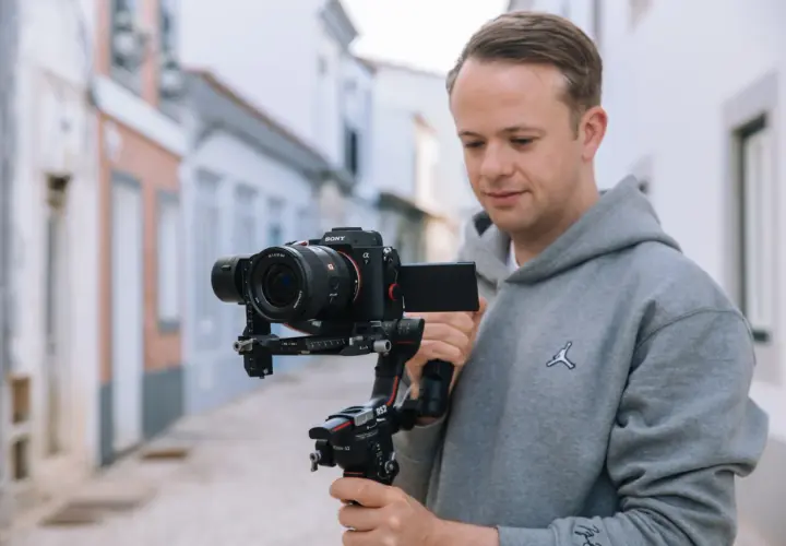 Mężczyzna trzyma profesjonalny aparat do filmowania Sony Alpha 7 na stabilizatorze Ronin S2.