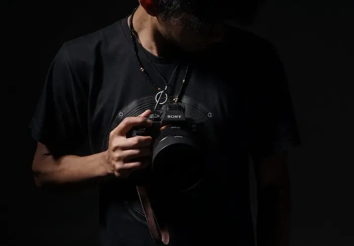 Mężczyzna z aparatem Sony, gotowy do uchwycenia wyjątkowych chwil. Szukasz inspiracji, jak znaleźć fotografa ślubnego?