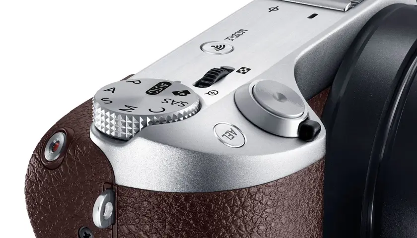 Zbliżenie na górną część eleganckiej, brązowej obudowy aparatu samsung lustrzanka cyfrowa. Widoczny pokrętło trybów i przyciski.