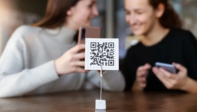 Dwie dziewczyny próbują zeskanować kod QR aparatem telefonu. Proste jak budowa cepa!