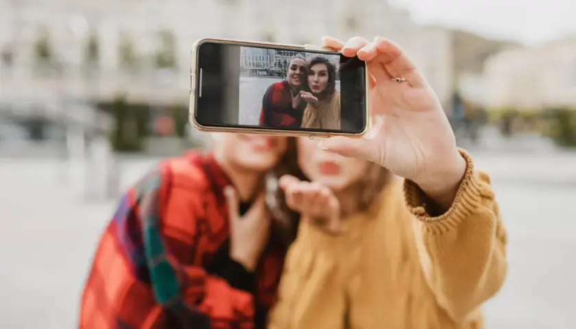 Dwie przyjaciółki robią sobie selfie telefonem. Chcesz wywołać zdjęcia z telefonu? To proste!