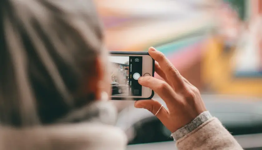 Dłoń trzyma smartfon, robiąc zdjęcie. Aby uzyskać czyste ujęcia, pamiętaj, jak wyczyścić aparat w telefonie.