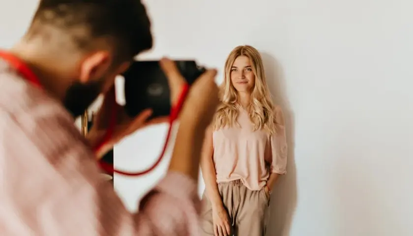 Fotograf robi zdjęcie uśmiechniętej blondynce. Zastanawiasz się, ile kosztuje sesja u fotografa?