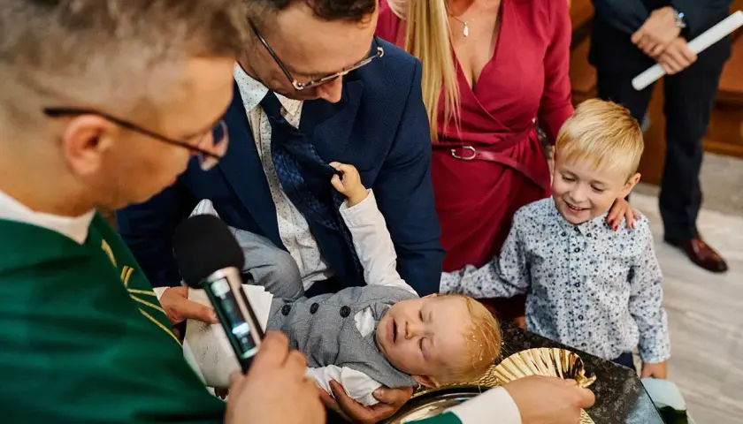 Chrzest dziecka w kościele, rodzice i ksiądz.
