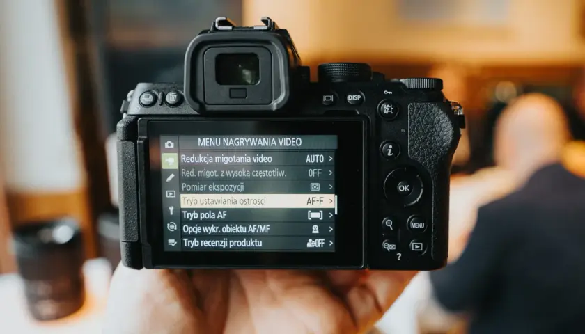 Dłoń trzyma aparat cyfrowy z widocznym menu nagrywania wideo.