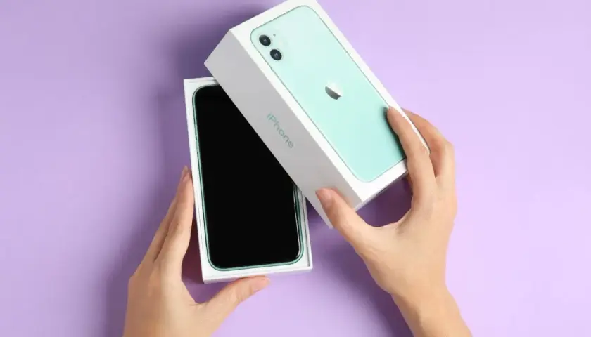 Ręce rozpakowują zielony iPhone 11. Aparat tego modelu pozwala robić świetne zdjęcia.