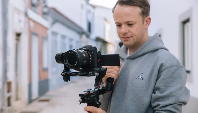 Mężczyzna trzyma profesjonalny aparat do filmowania Sony Alpha 7 na stabilizatorze Ronin S2.
