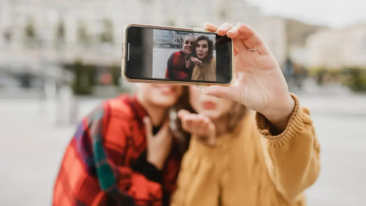 Dwie przyjaciółki robią sobie selfie telefonem. Chcesz wywołać zdjęcia z telefonu? To proste!