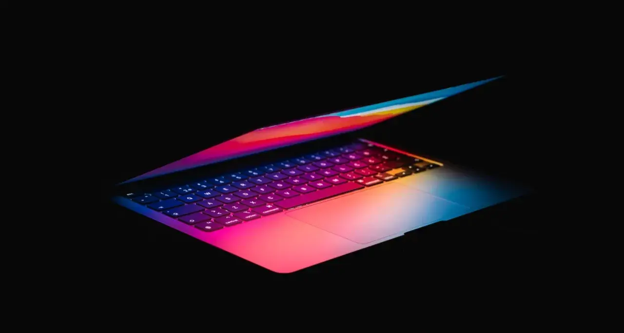 Kolorowy laptop, idealny do pracy w Photoshopie, z podświetlaną klawiaturą w odcieniach tęczy.