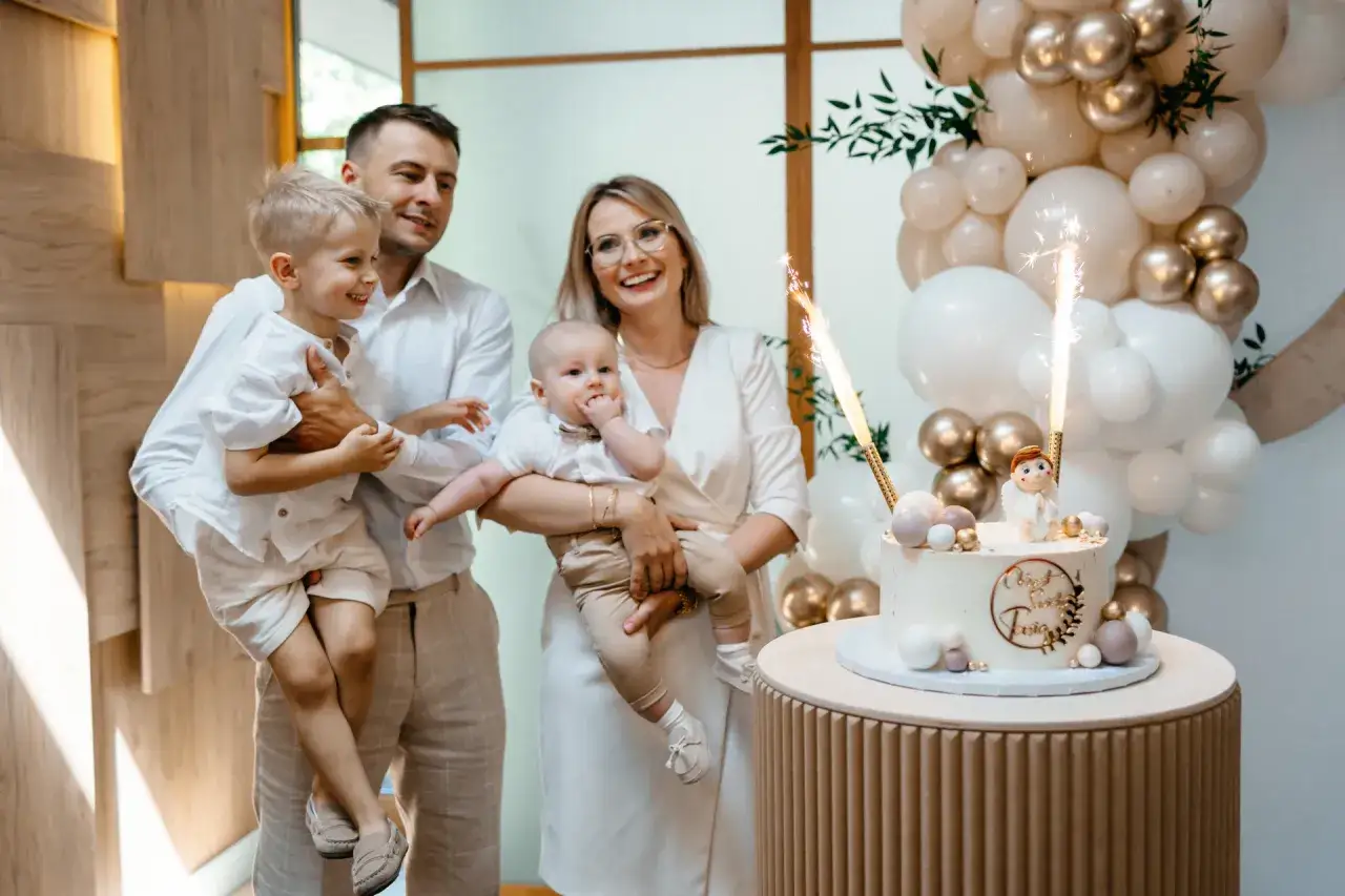 Rodzina świętuje chrzest dziecka przy torcie z fontannami. Zastanawiasz się, ile kosztuje fotograf na chrzest?