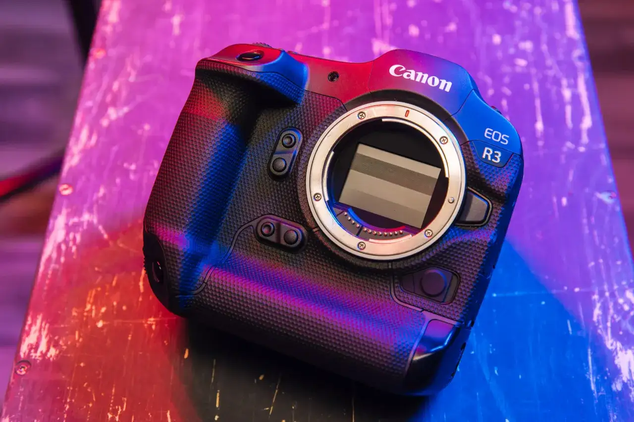 Profesjonalny aparat Canon EOS R3, jaki aparat do filmowania, z obiektywem w kolorach neonowego różu i błękitu.