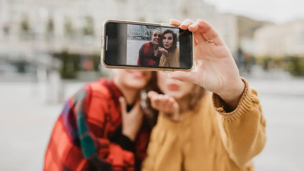 Dwie przyjaci&oacute;łki robią sobie selfie telefonem. Zastanawiasz się, czy można wywołać zdjęcia z telefonu u fotografa? Tak, to możliwe!