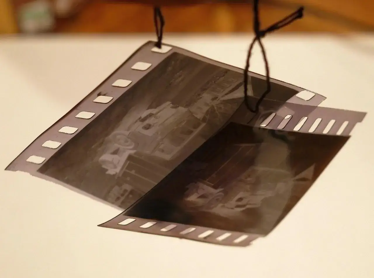 Wywoływanie zdjęć z aparatu jednorazowego: negatywy filmowe z widocznymi samochodami wiszą na sznurku.
