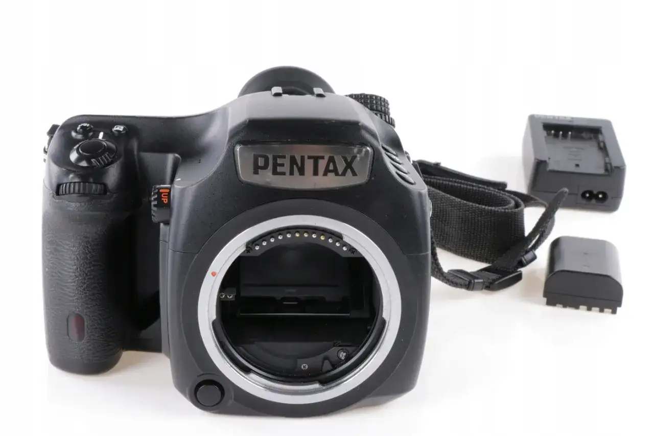 Czarna lustrzanka cyfrowa Pentax z paskiem i akcesoriami, gotowa do aukcji na Allegro.