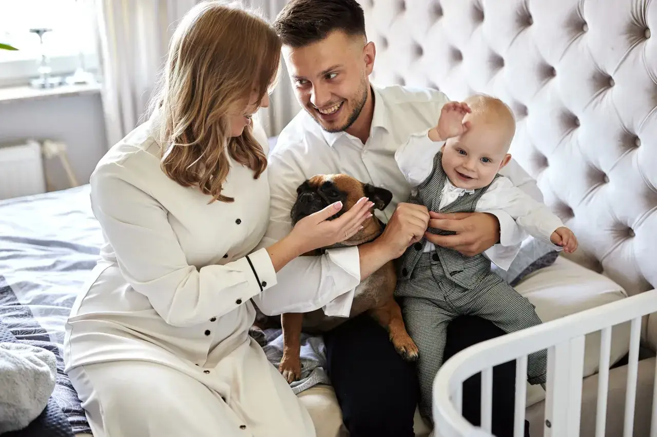 Szczęśliwa rodzina z pieskiem i dzieckiem na rękach. Zastanawiasz się, ile kosztuje fotograf na chrzest?