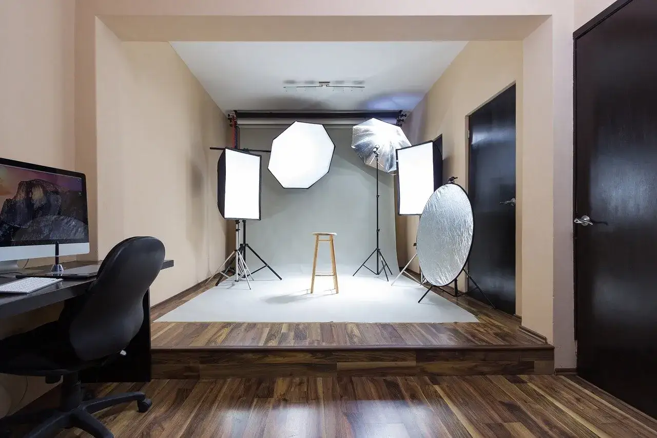 Studio do sesji produktowej. Widoczne lampy, statywy, tło i taboret. Idealne miejsce, by dowiedzieć się, jak zrobić zdjęcie produktu.