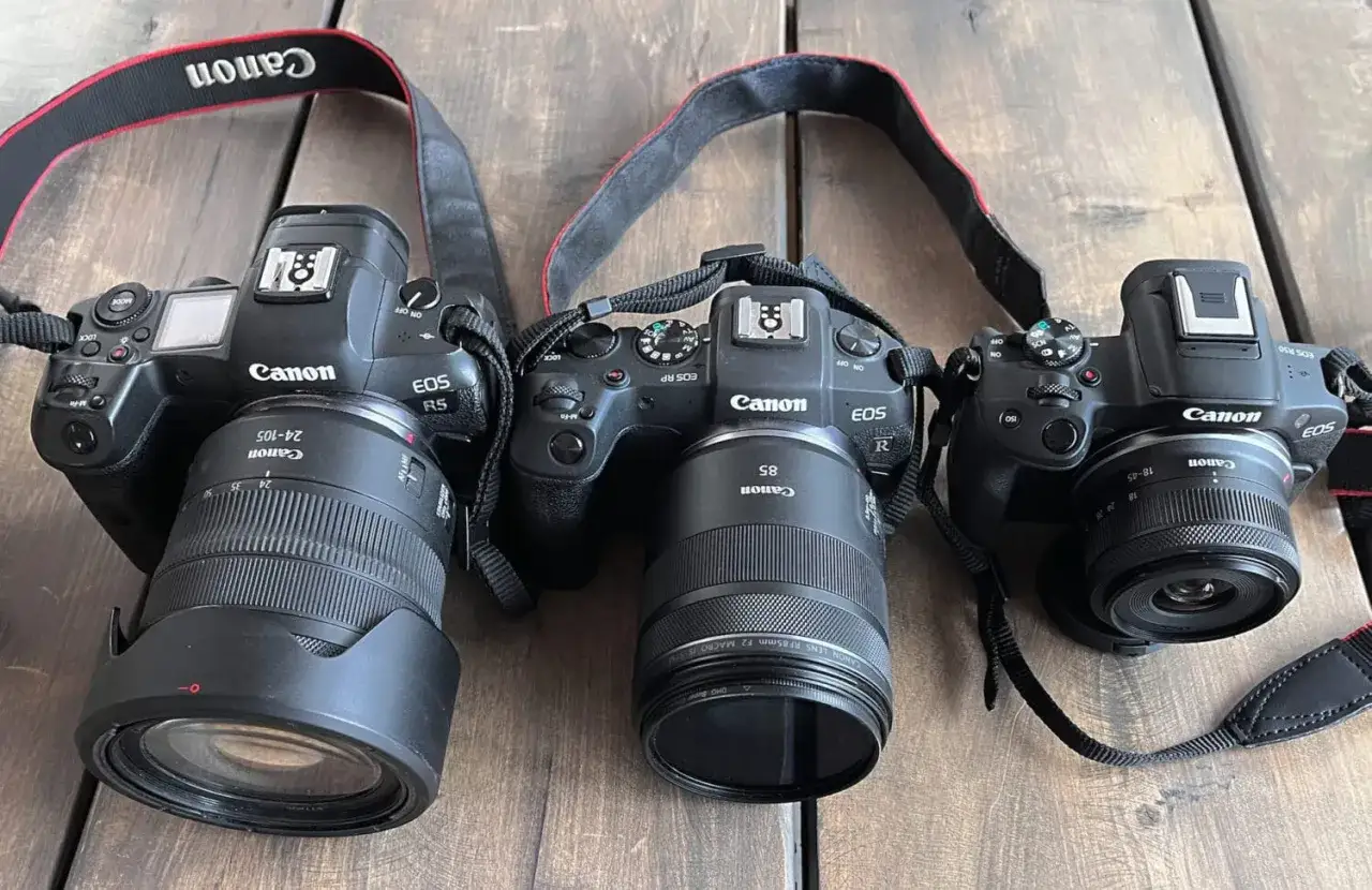 Trzy aparaty Canon EOS R, R5 i RP leżą obok siebie. Jaki aparat lustrzanka wybrać?